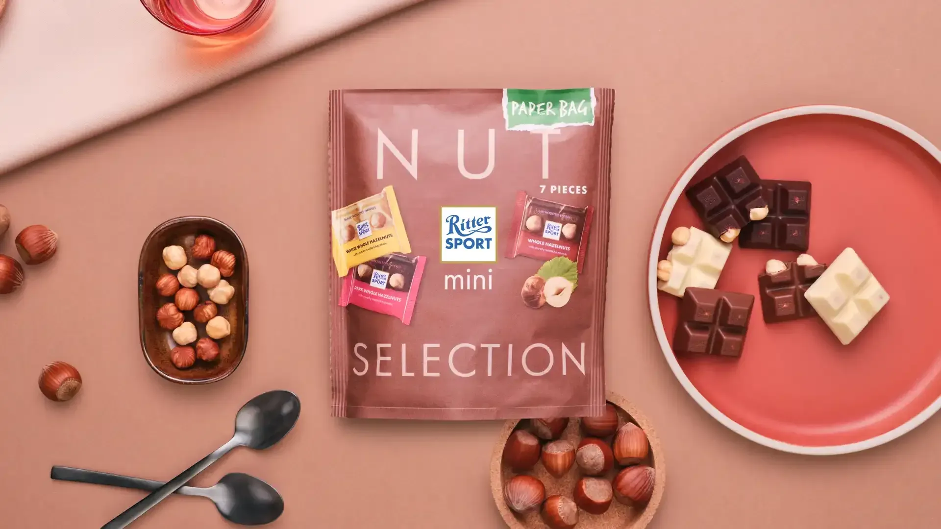 Ritter Sport chocolate bar packaging with cocoa beans, broken chocolate, and milk on a blue background.