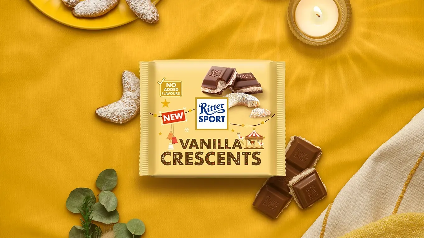 Verpackung einer blauen Schokoladentafel mit Nüssen, Schokoladenstückchen und dem Hinweis „55 % Kakaoanteil“ auf blauem Hintergrund