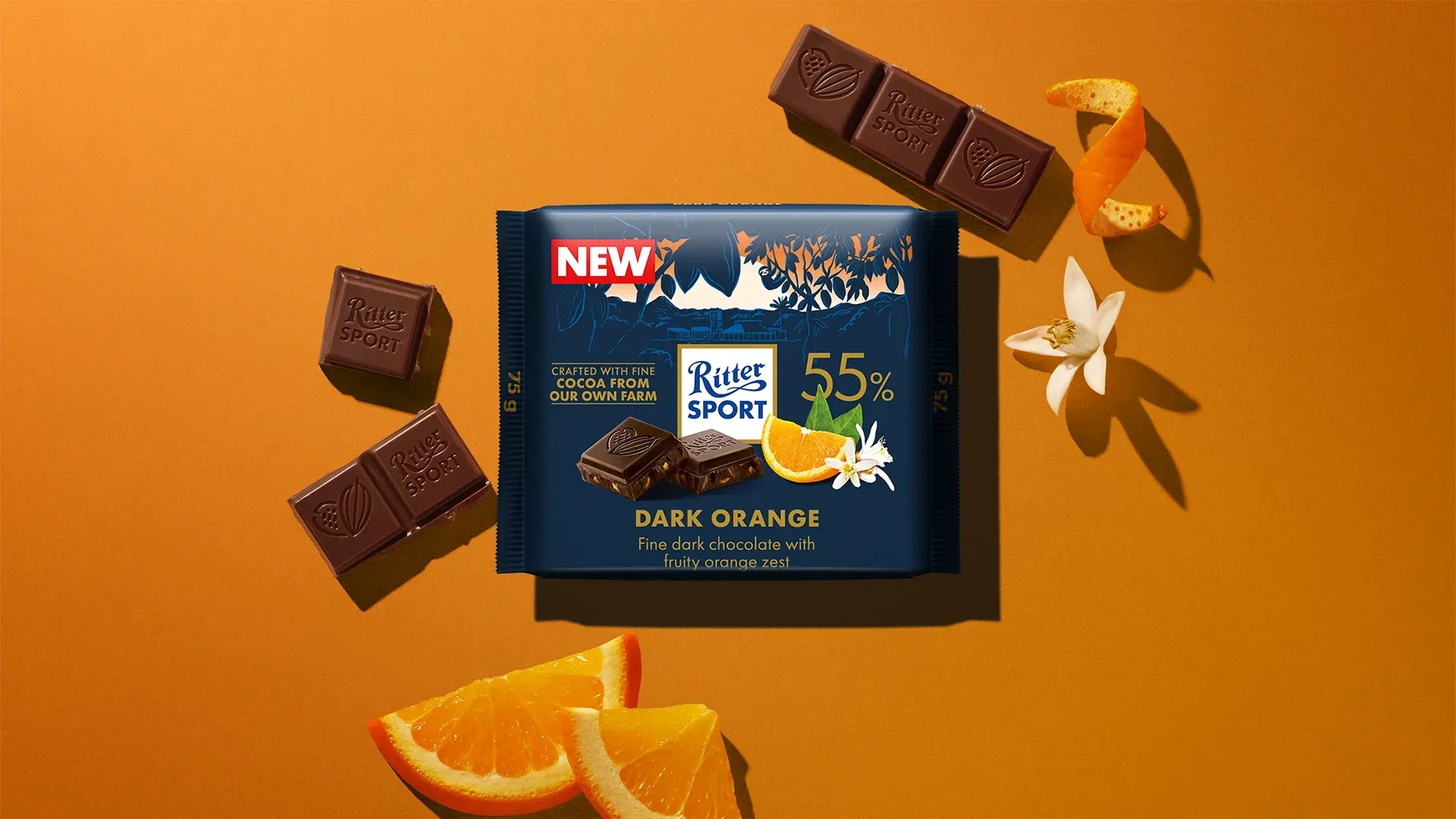 Ritter Sport chocolate bar packaging with cocoa beans, broken chocolate, and milk on a blue background.