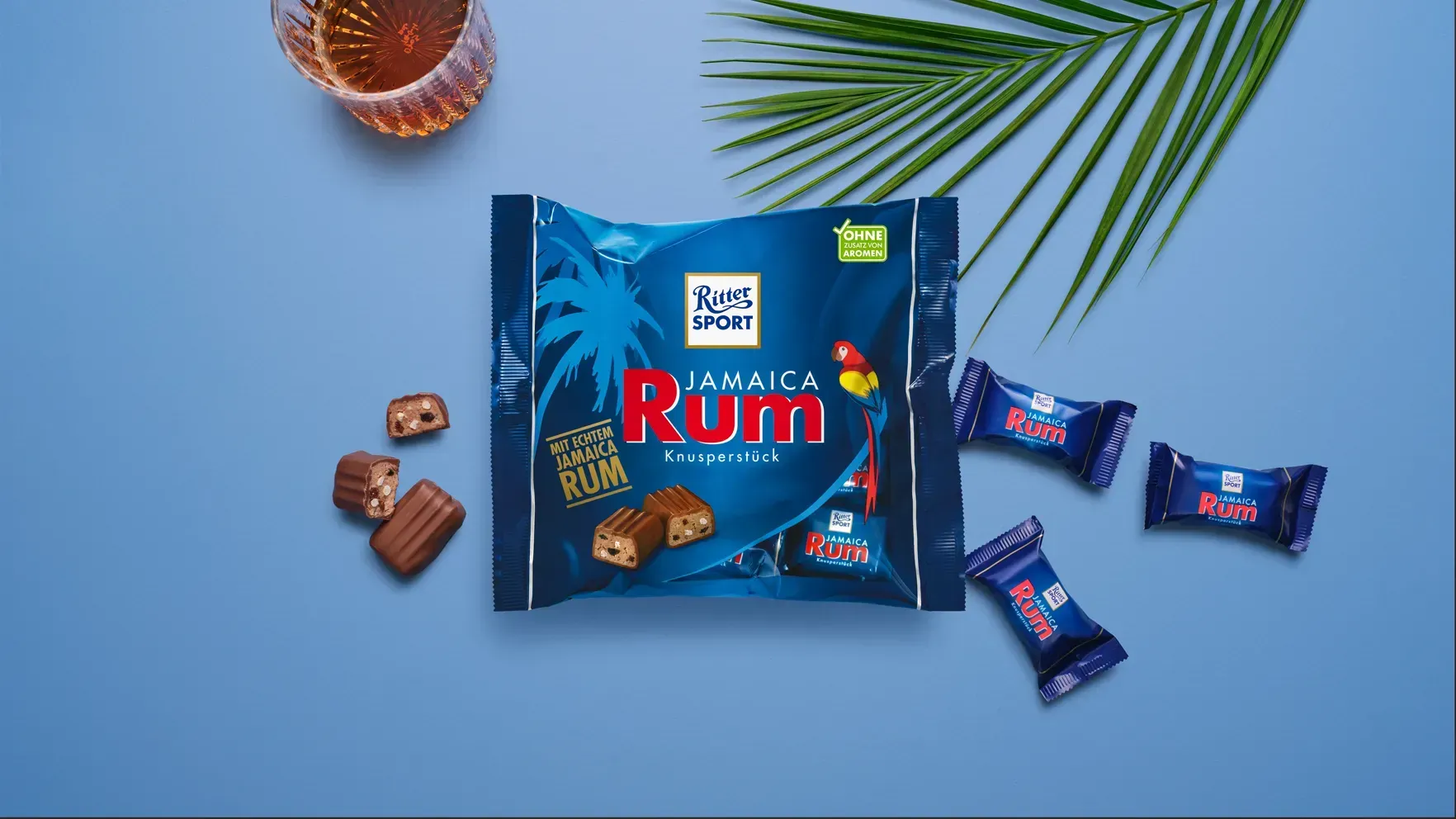 Verpackung einer blauen Schokoladentafel mit Nüssen, Schokoladenstückchen und dem Hinweis „55 % Kakaoanteil“ auf blauem Hintergrund