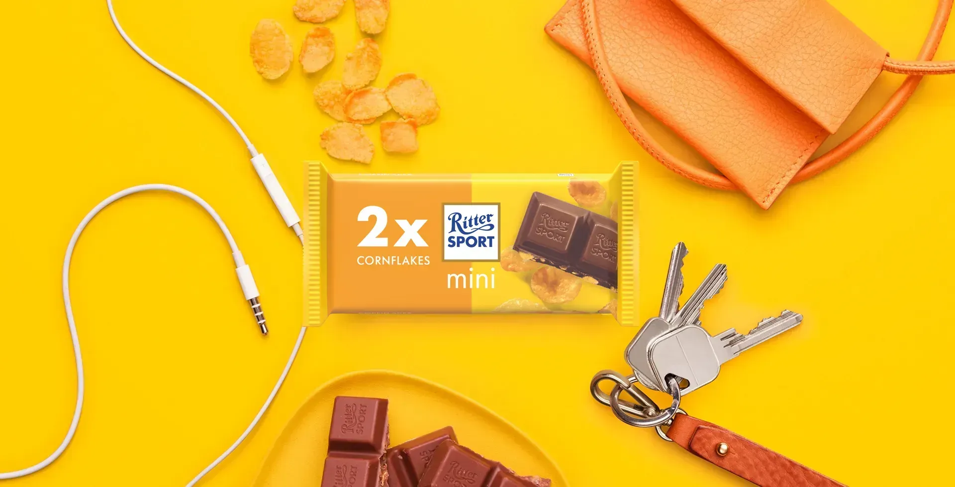 Ritter Sport chocolate bar packaging with cocoa beans, broken chocolate, and milk on a blue background.