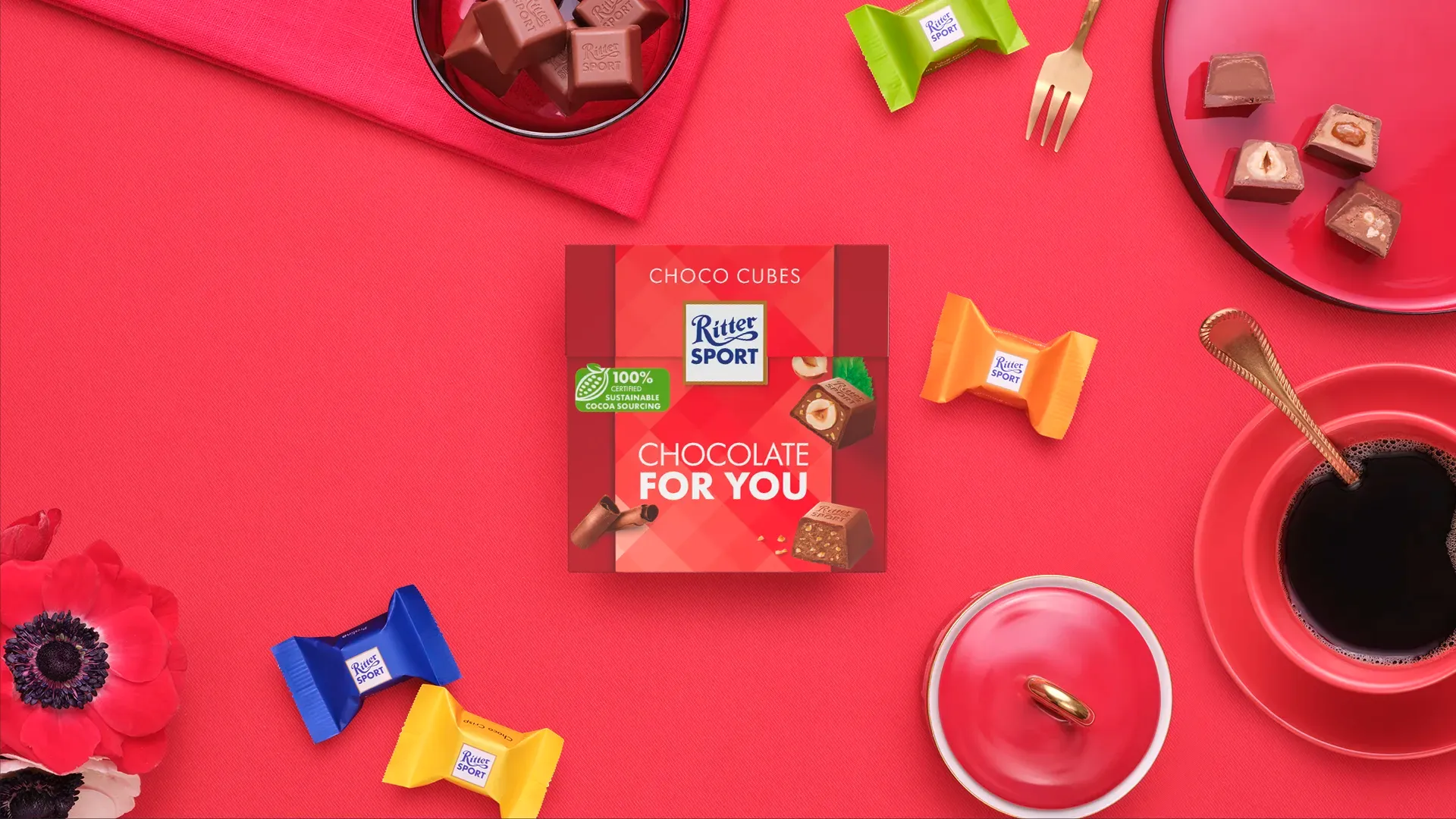 Ritter Sport chocolate bar packaging with cocoa beans, broken chocolate, and milk on a blue background.