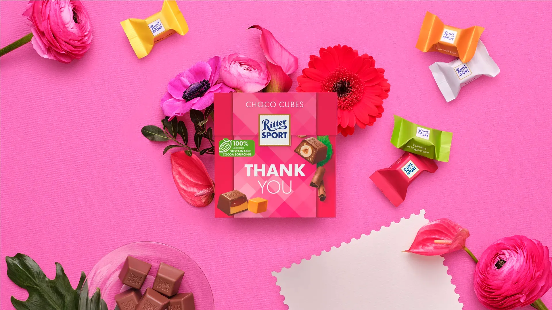 Ritter Sport chocolate bar packaging with cocoa beans, broken chocolate, and milk on a blue background.