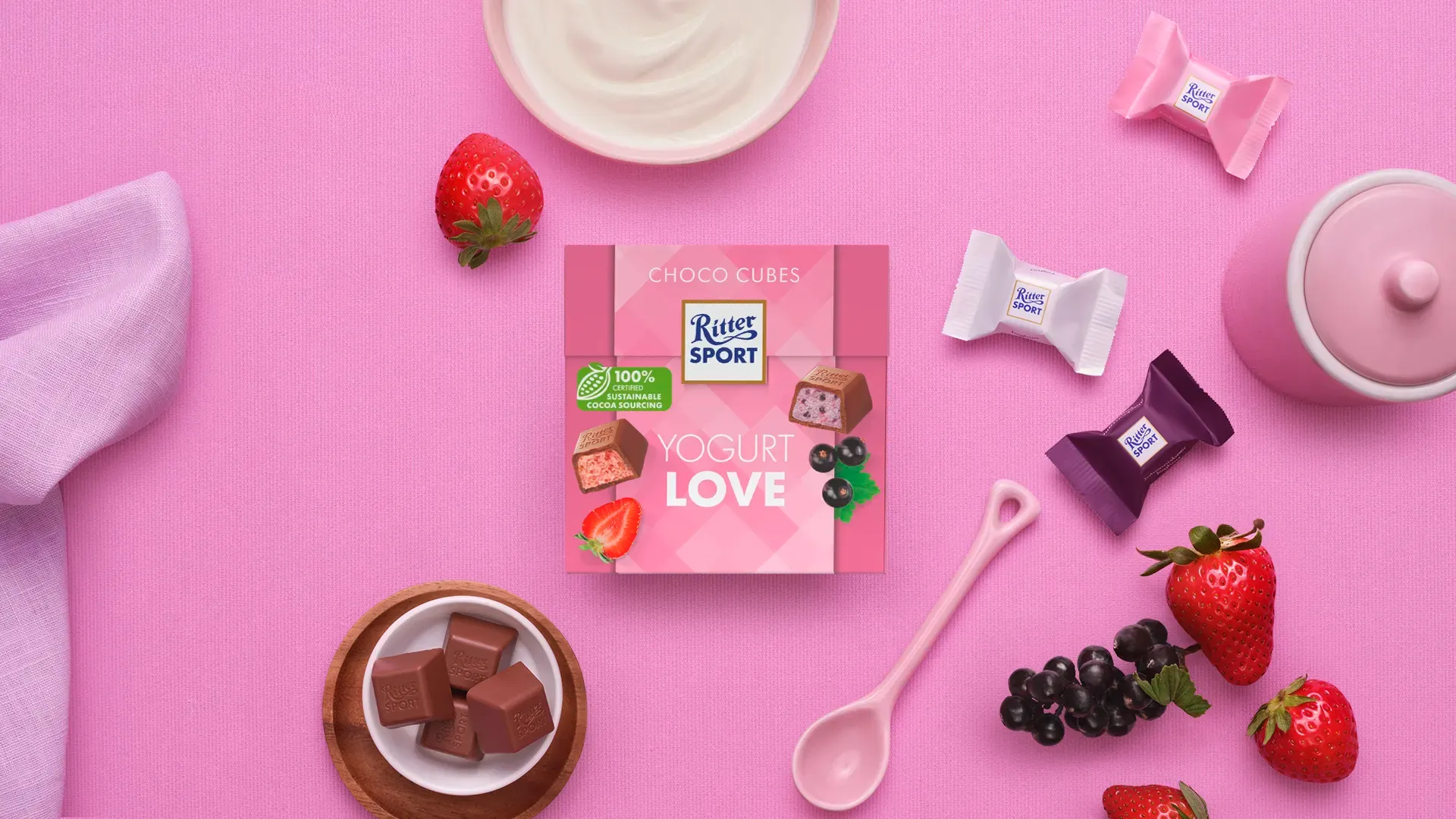 Ritter Sport chocolate bar packaging with cocoa beans, broken chocolate, and milk on a blue background.
