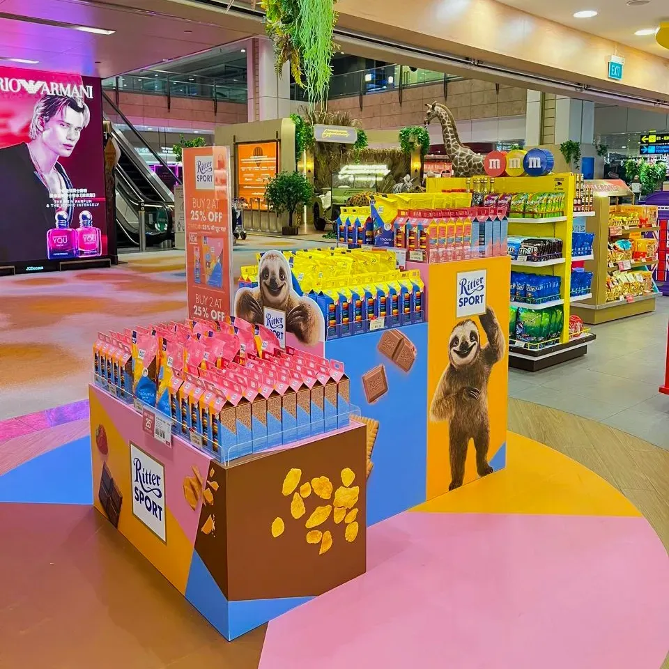 Colourful chocolate display in a shopping mall, with colorful shelves and sloth decorations.