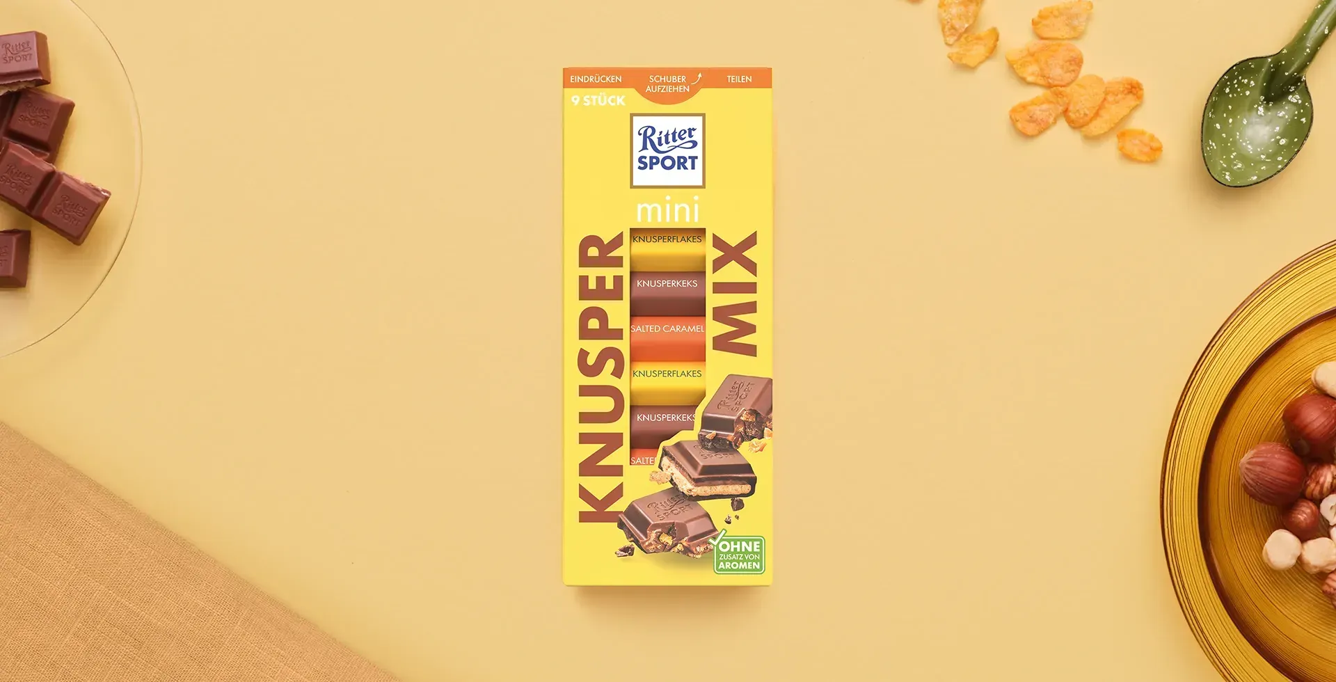 Verpackung einer blauen Schokoladentafel mit Nüssen, Schokoladenstückchen und dem Hinweis „55 % Kakaoanteil“ auf blauem Hintergrund