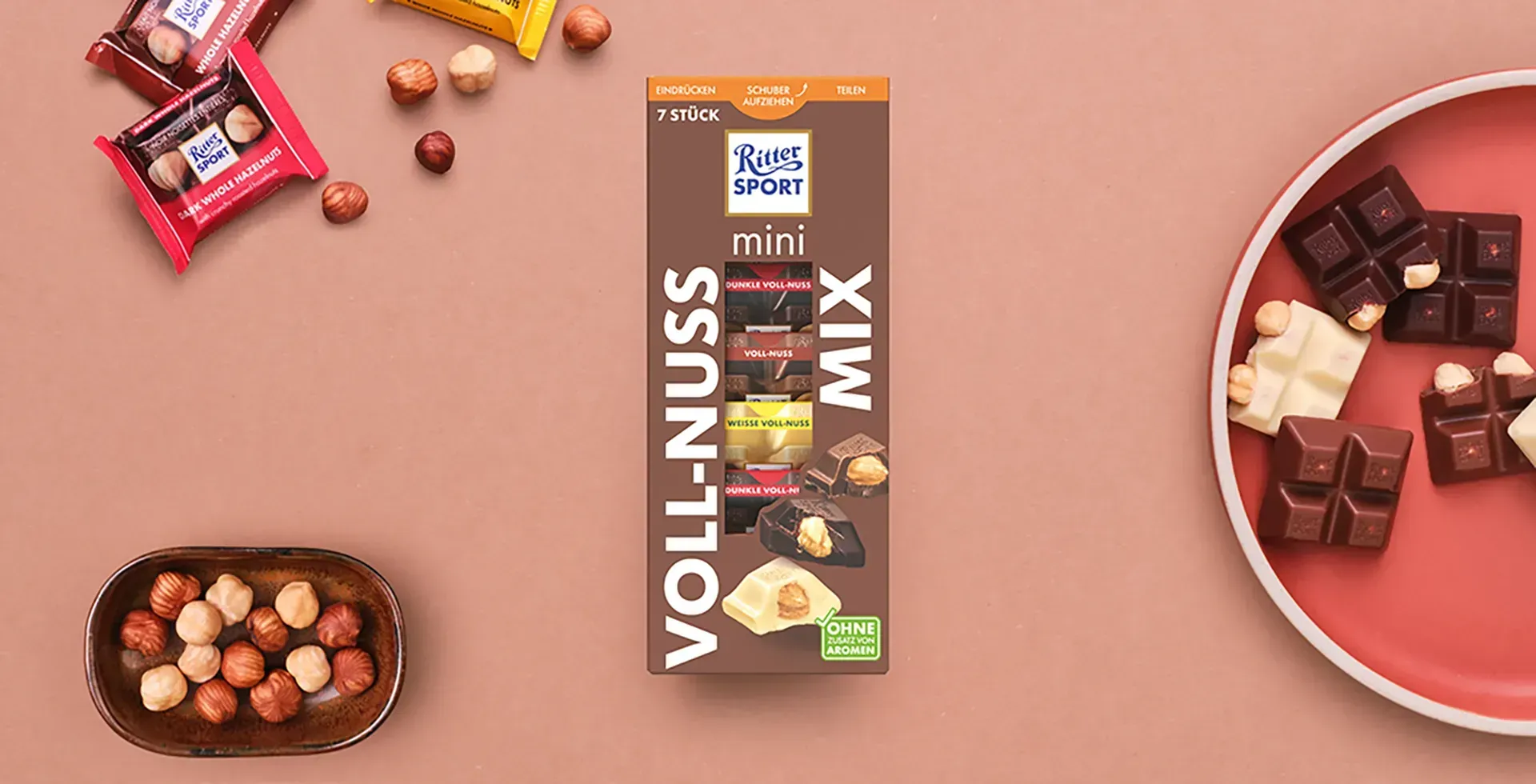 Verpackung einer blauen Schokoladentafel mit Nüssen, Schokoladenstückchen und dem Hinweis „55 % Kakaoanteil“ auf blauem Hintergrund