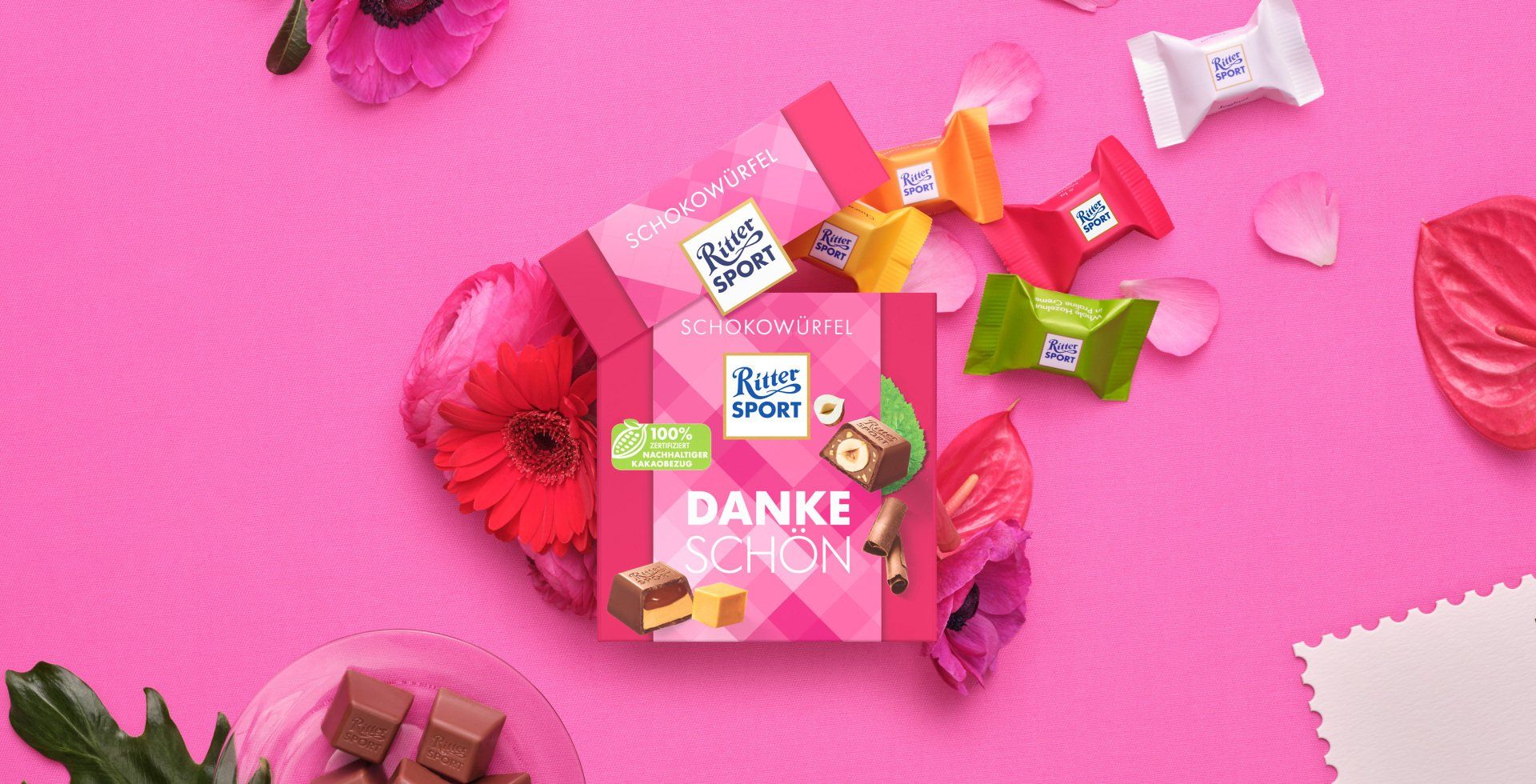Verpackung einer blauen Schokoladentafel mit Nüssen, Schokoladenstückchen und dem Hinweis „55 % Kakaoanteil“ auf blauem Hintergrund