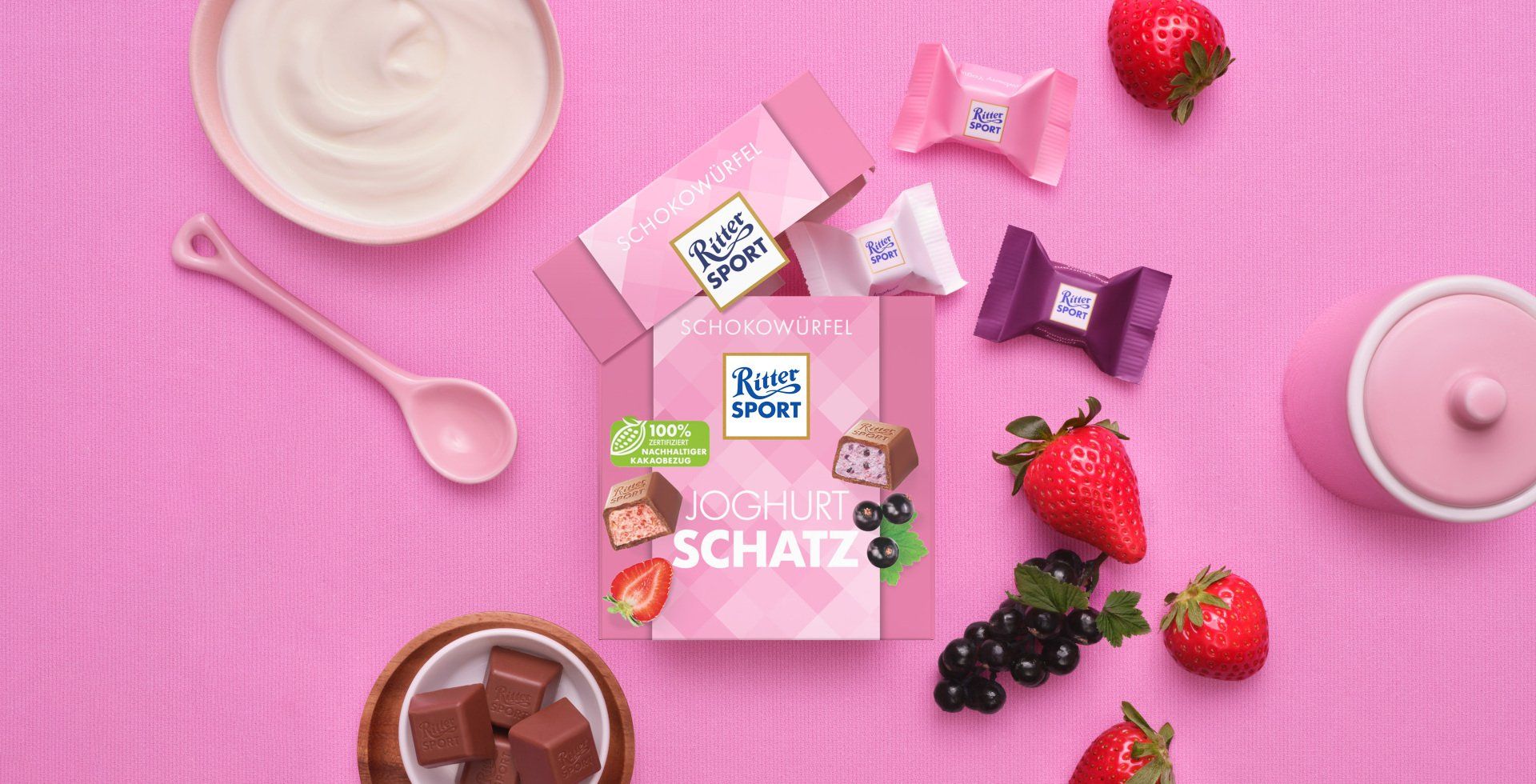 Verpackung einer blauen Schokoladentafel mit Nüssen, Schokoladenstückchen und dem Hinweis „55 % Kakaoanteil“ auf blauem Hintergrund