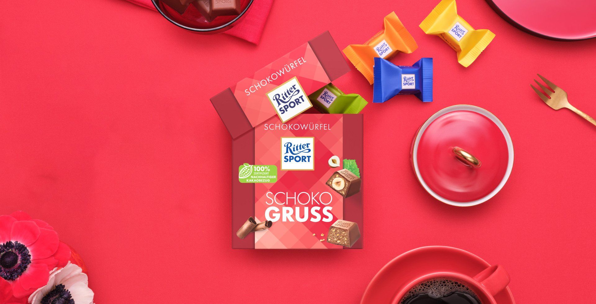 Verpackung einer blauen Schokoladentafel mit Nüssen, Schokoladenstückchen und dem Hinweis „55 % Kakaoanteil“ auf blauem Hintergrund