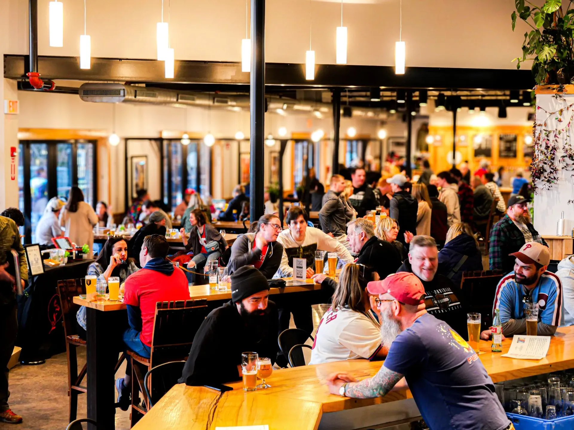 Interior view of a crowded brewery with people seated at tables and the bar.