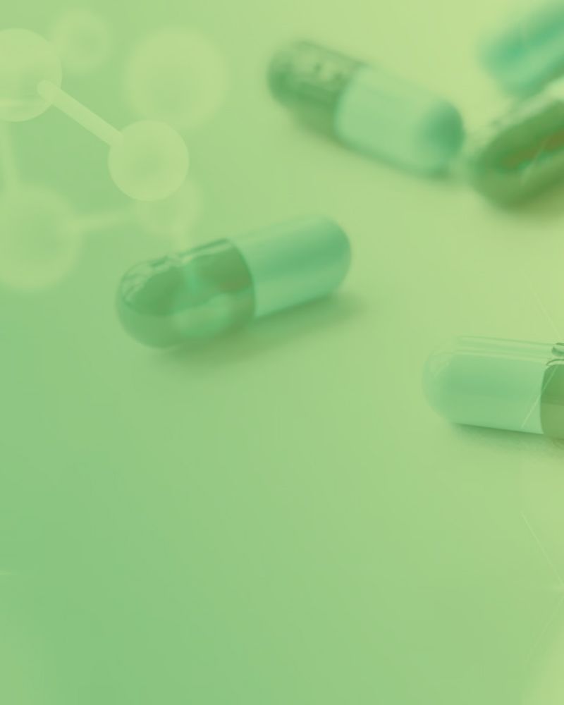 A group of green pills are sitting on a green surface.