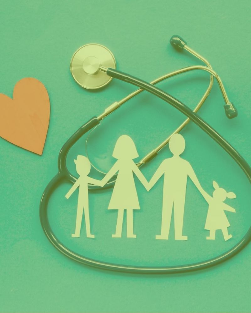 A paper cut out of a family holding hands next to a stethoscope and a heart.