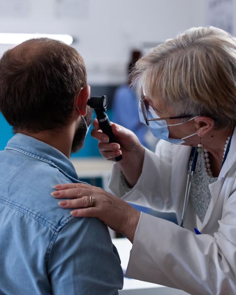 A doctor is examining a man 's ear with an otoscope.