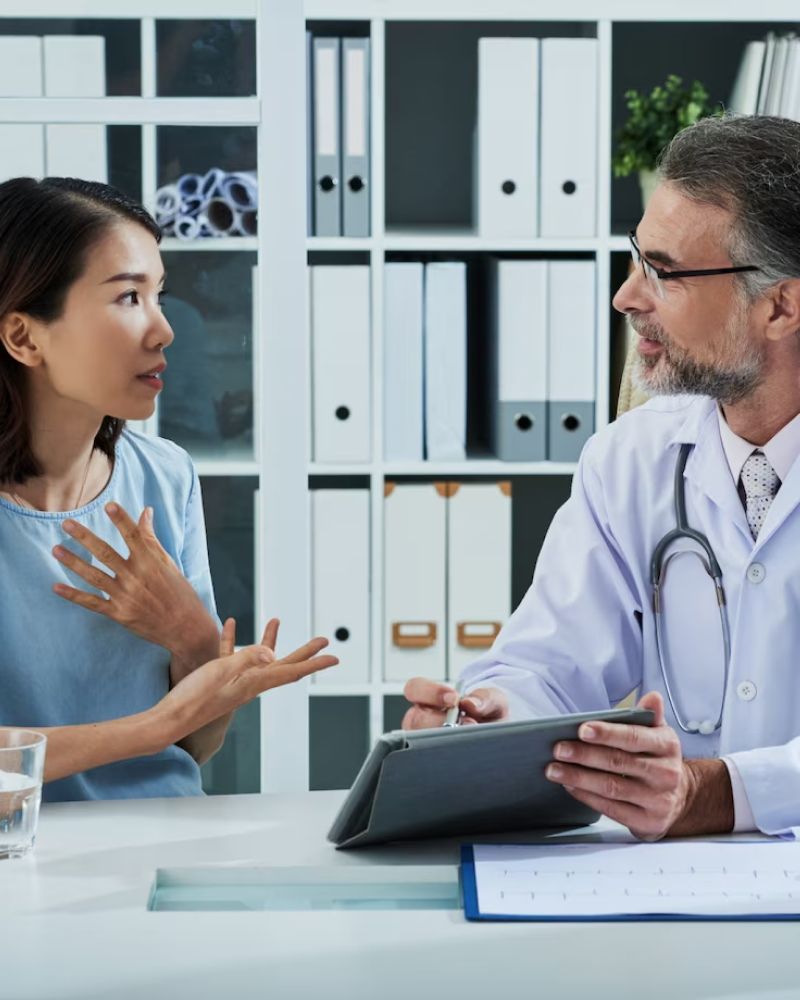 A doctor is talking to a patient while holding a tablet