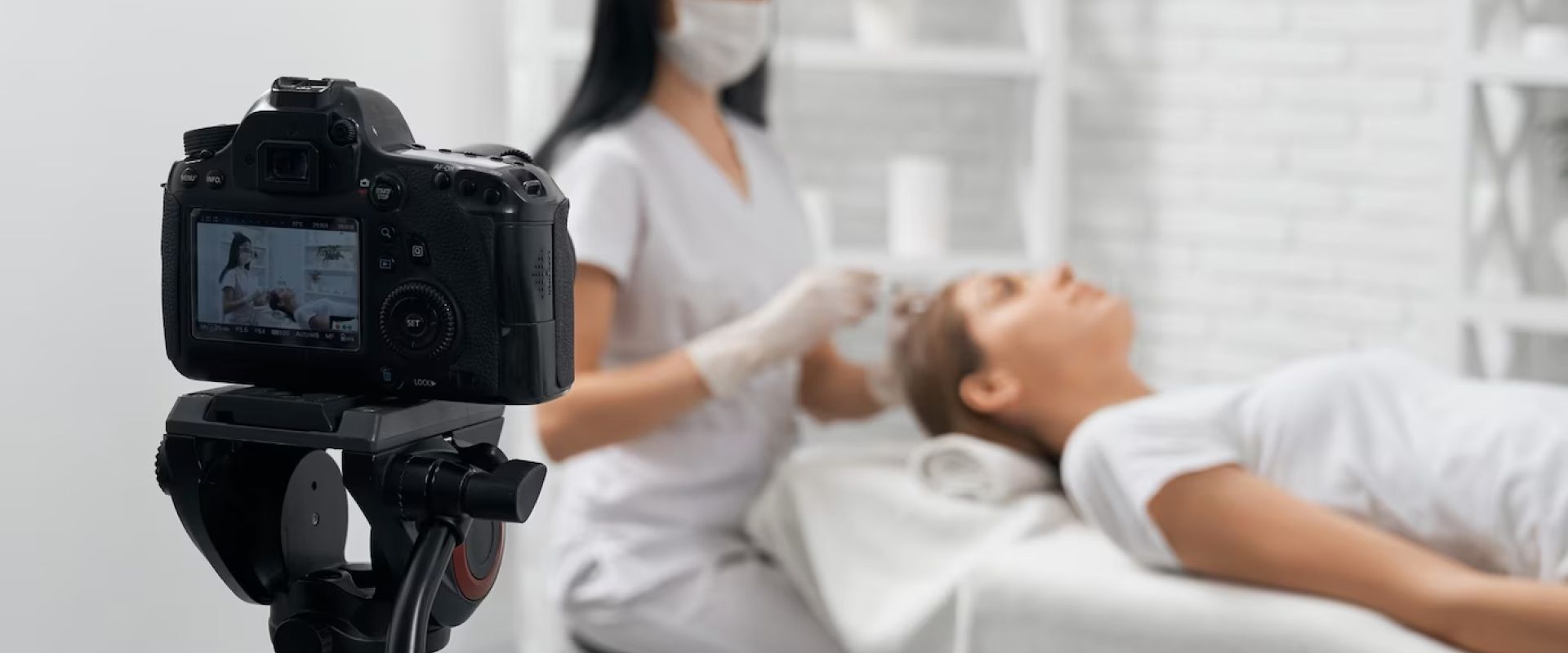 A woman is getting a facial treatment in a beauty salon and a camera is taking a picture of her.