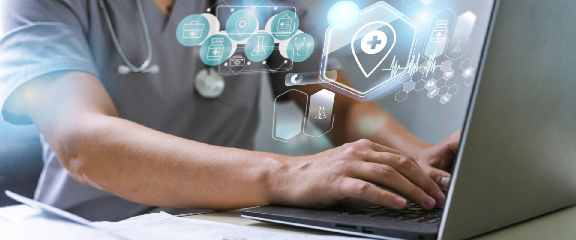 A doctor is typing on a laptop computer with a stethoscope around his neck.