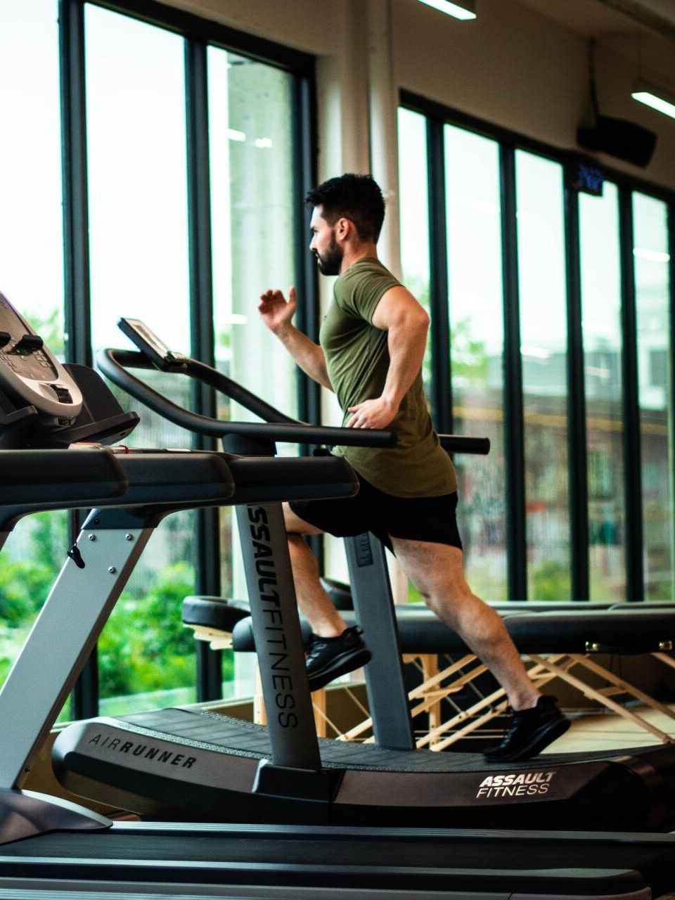 A man is running on a treadmill in a gym.