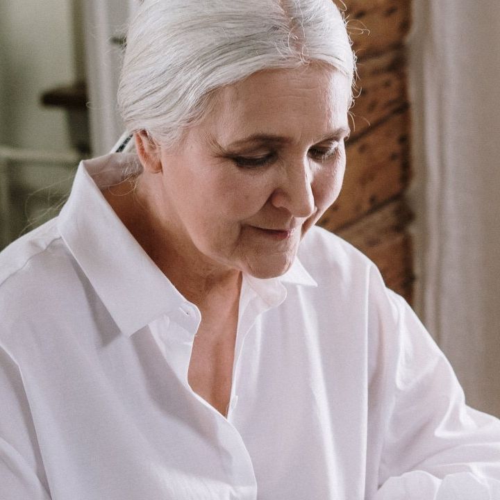 A woman with white hair is wearing a white shirt.