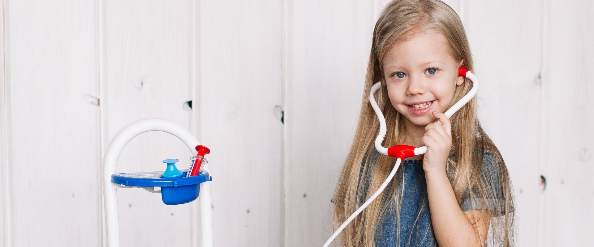 A little girl is playing doctor with a stethoscope.