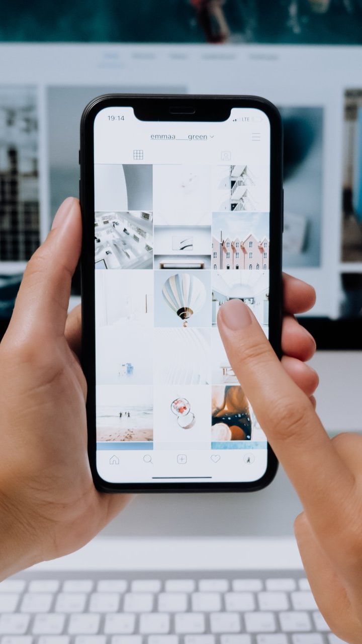 A person is holding a cell phone in their hand and pointing at it.