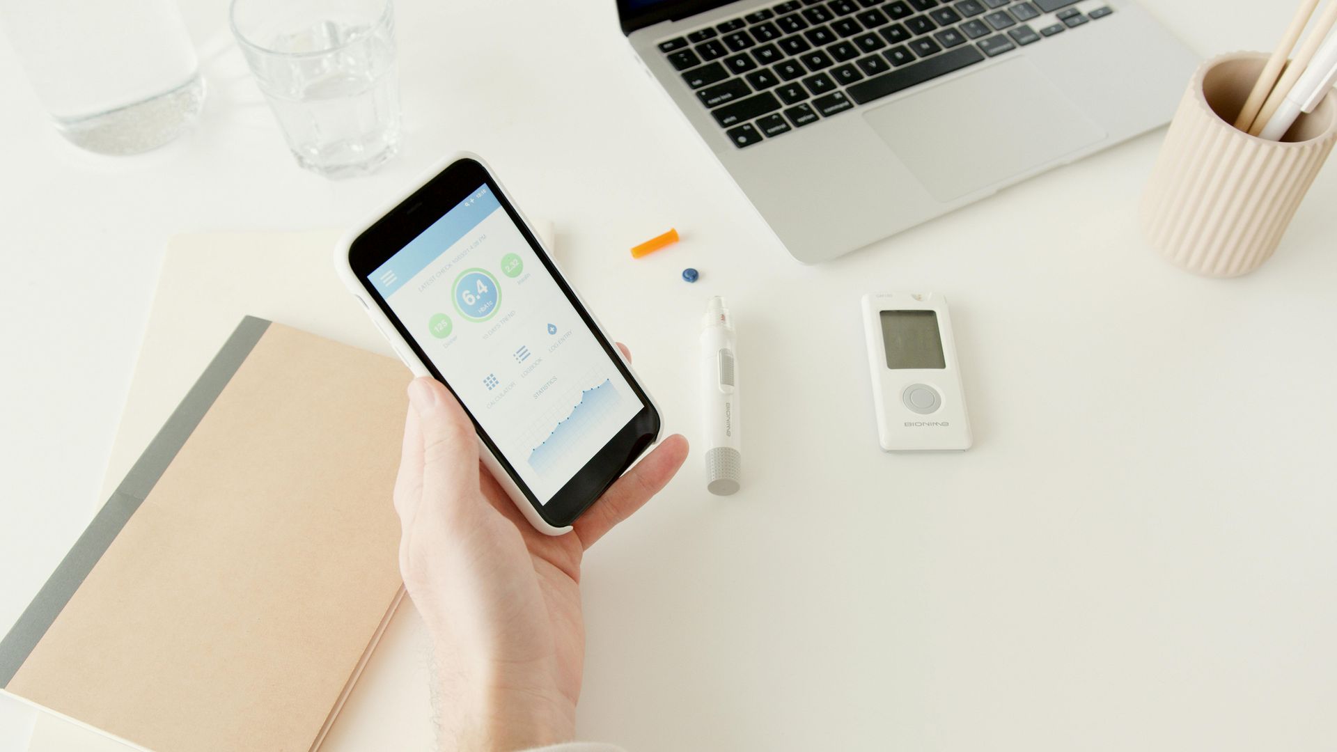 A person is holding a cell phone in front of a laptop.