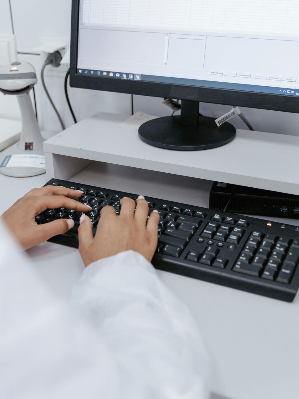 A person is typing on a keyboard in front of a computer monitor