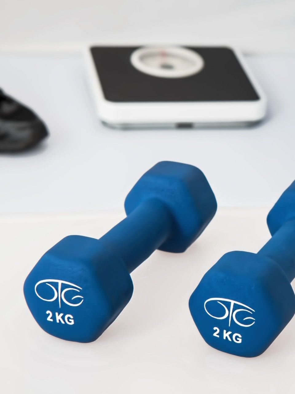 A pair of blue dumbbells with a weight scale in the background