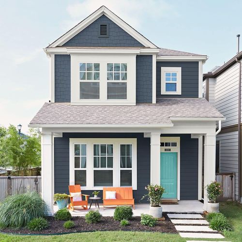 gray exterior of home with white trim, blue sky and green landscaped front yard