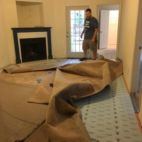 removing old tan carpeting in a room with a fireplace, man standing in the corner