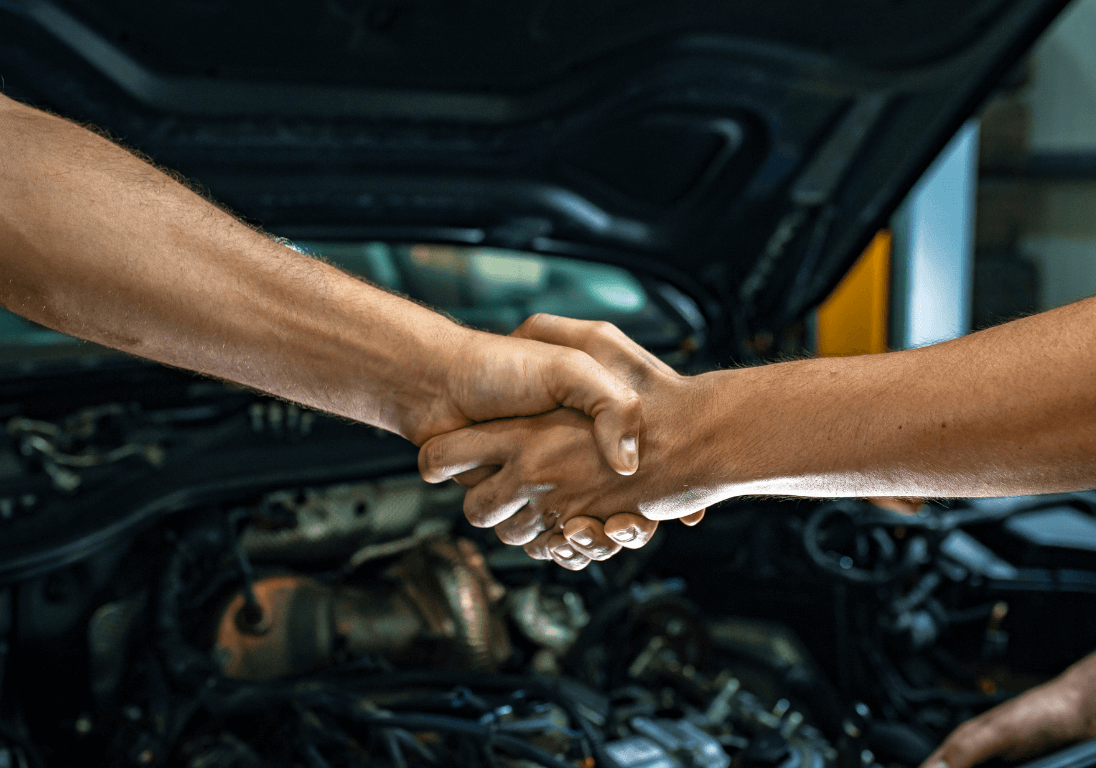 shaking hands in front of a car