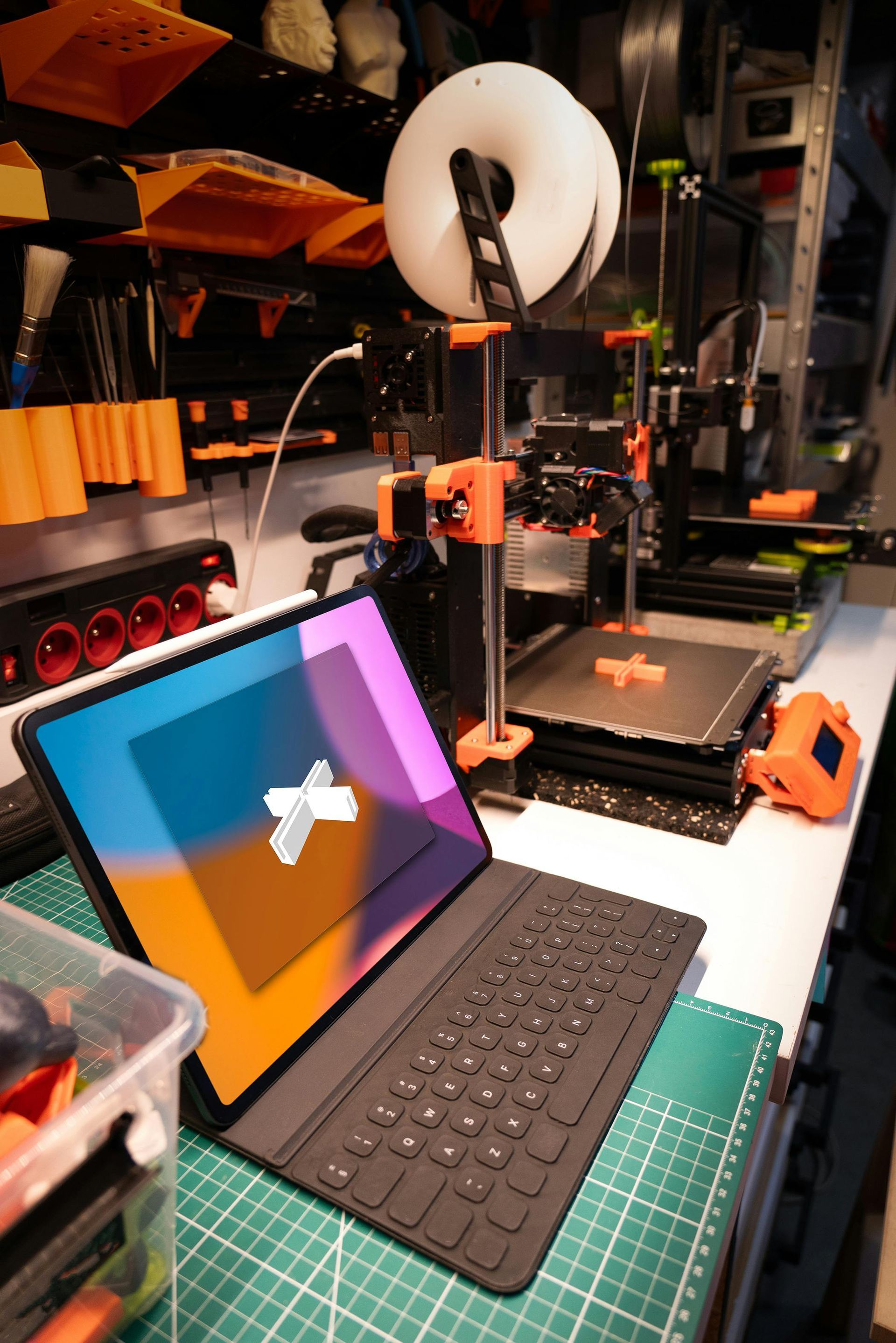 3D printer workspace with tablet, keyboard, ring light, and tools on a desk