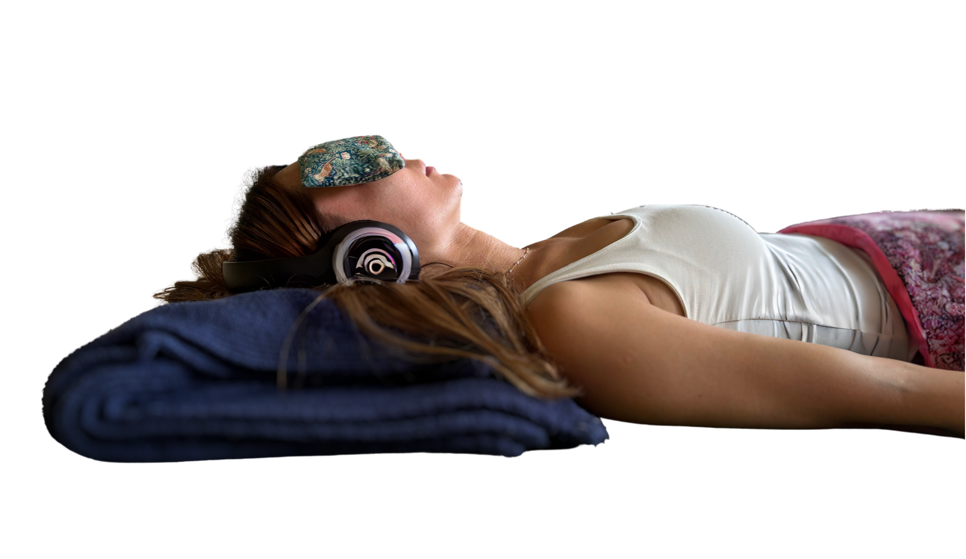 A woman is laying on the floor wearing headphones and a sleep mask.