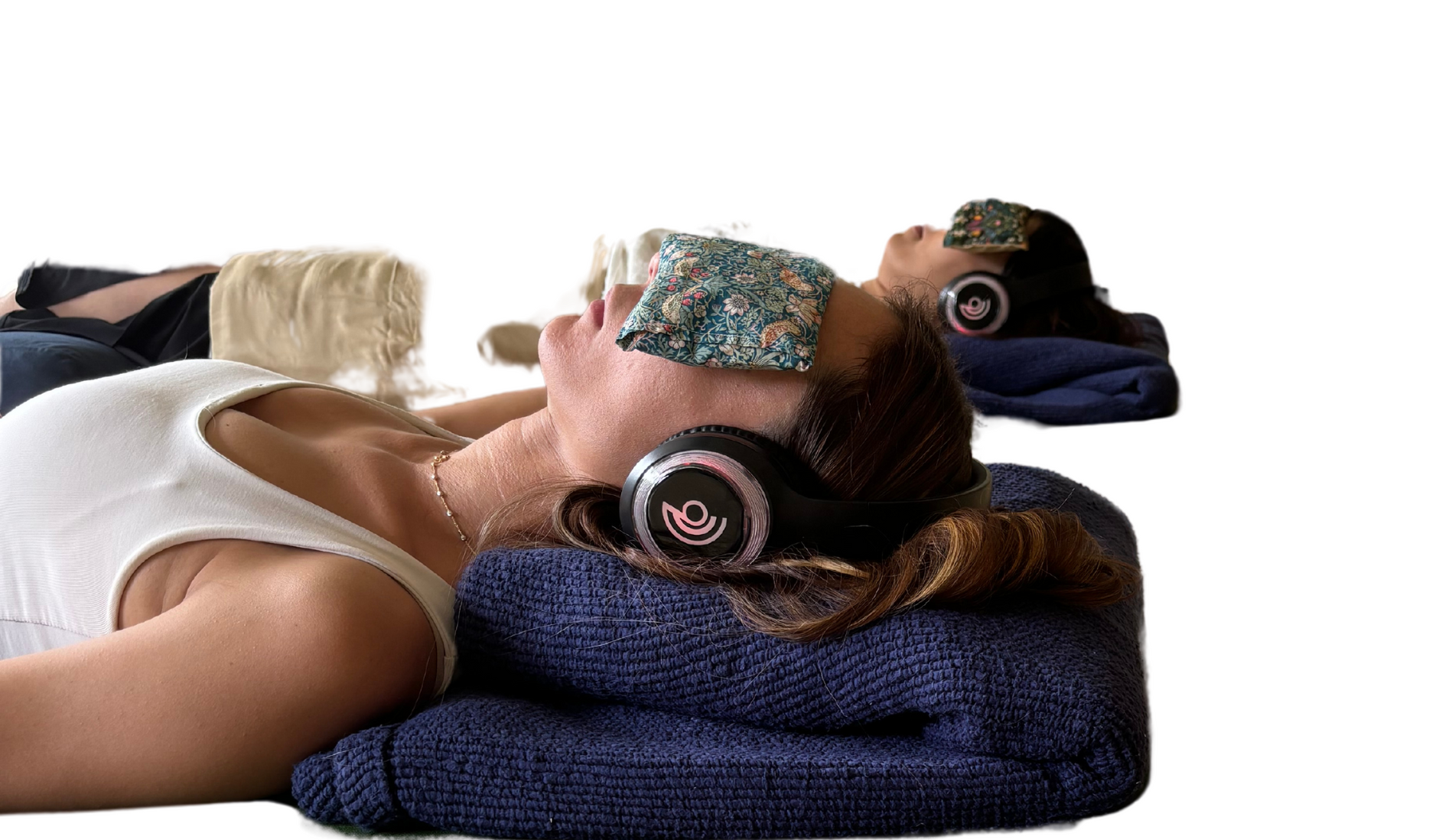 A woman is laying on a towel with headphones on her head.
