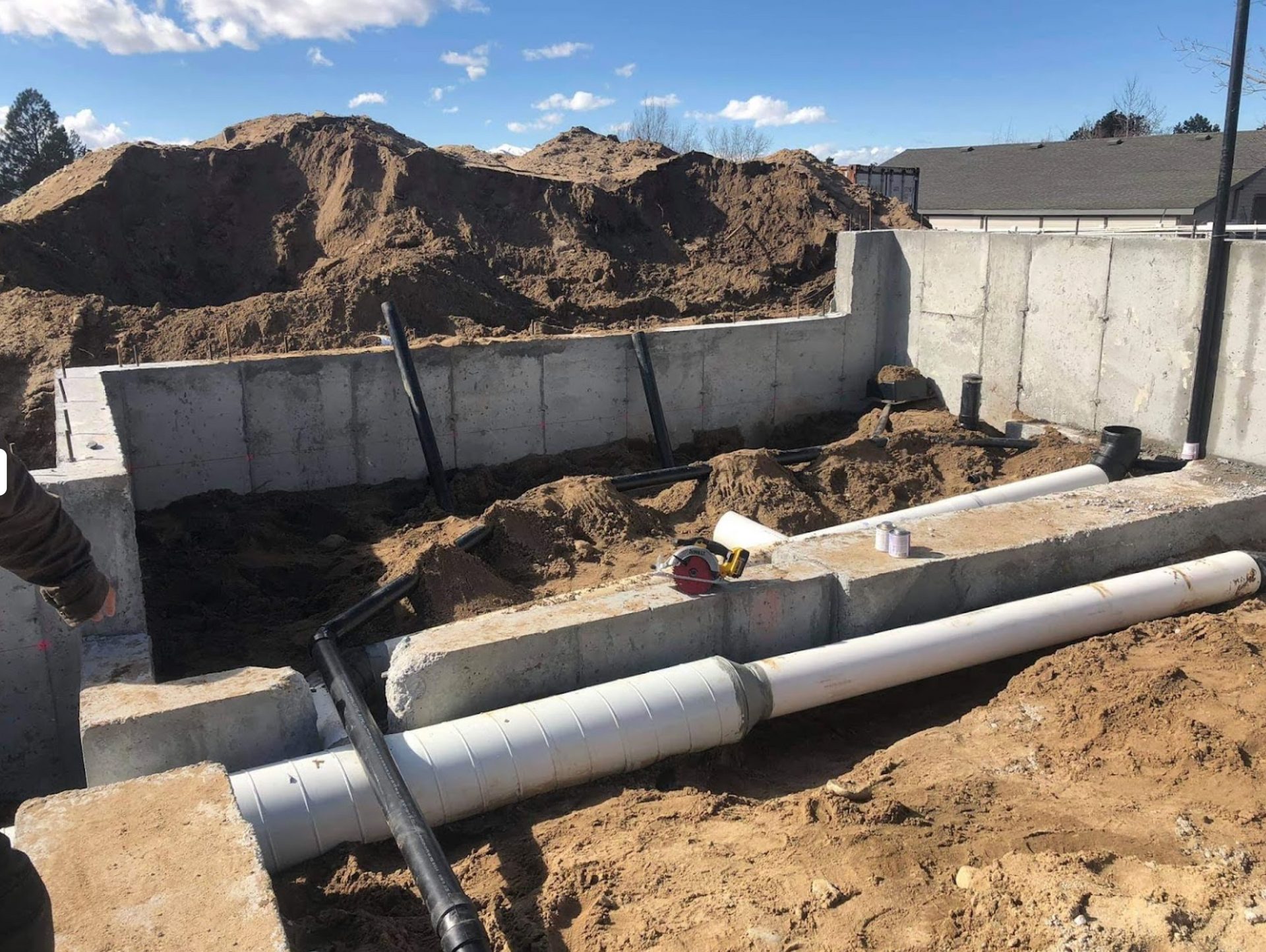 A concrete wall is being built next to a pile of dirt and pipes.