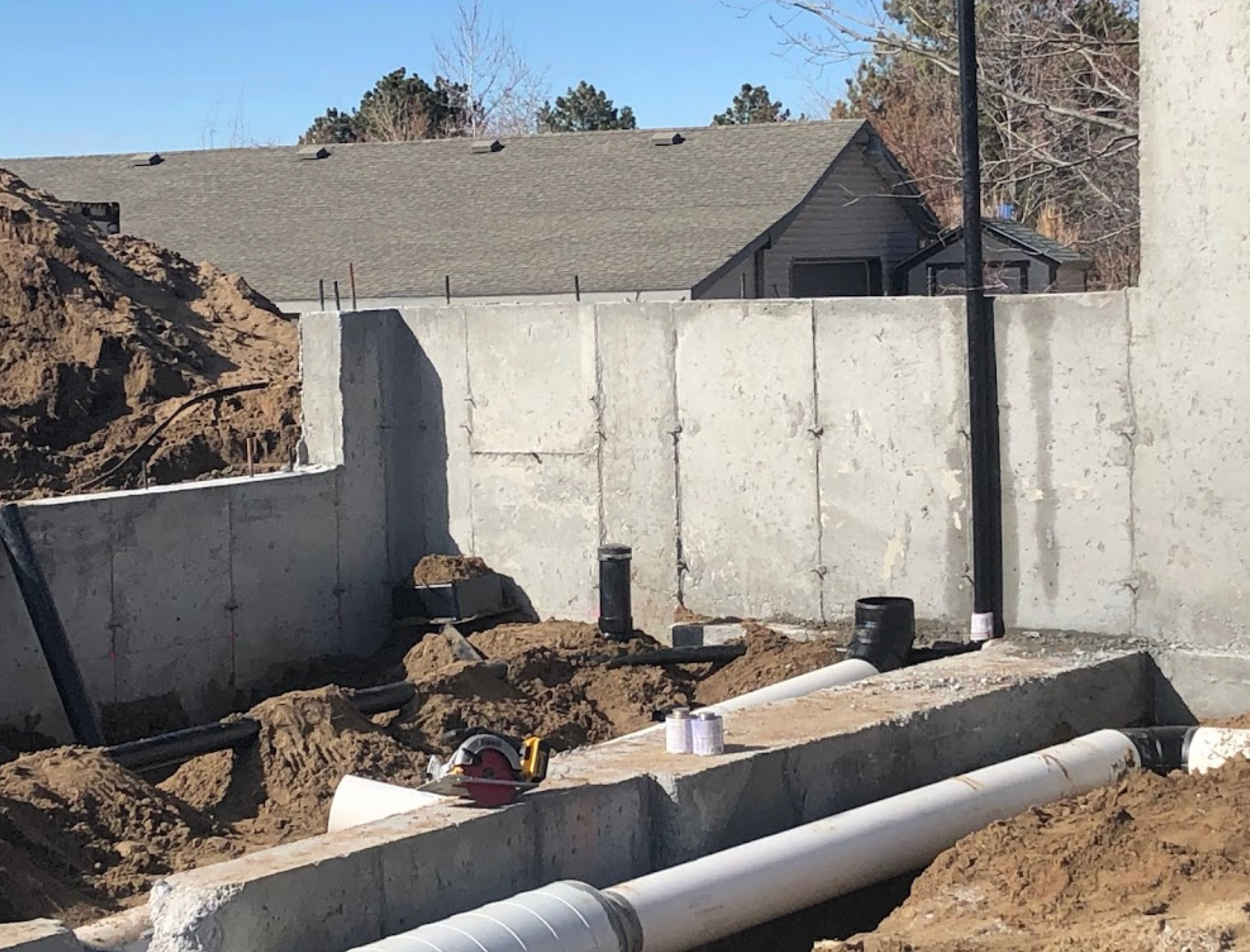 A concrete wall is being built next to a pile of dirt and pipes