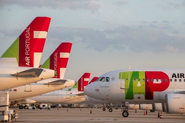 Aviões da Air Portugal estacionados na pista, com caudas vermelhas e verdes e o logotipo da companhia aérea.