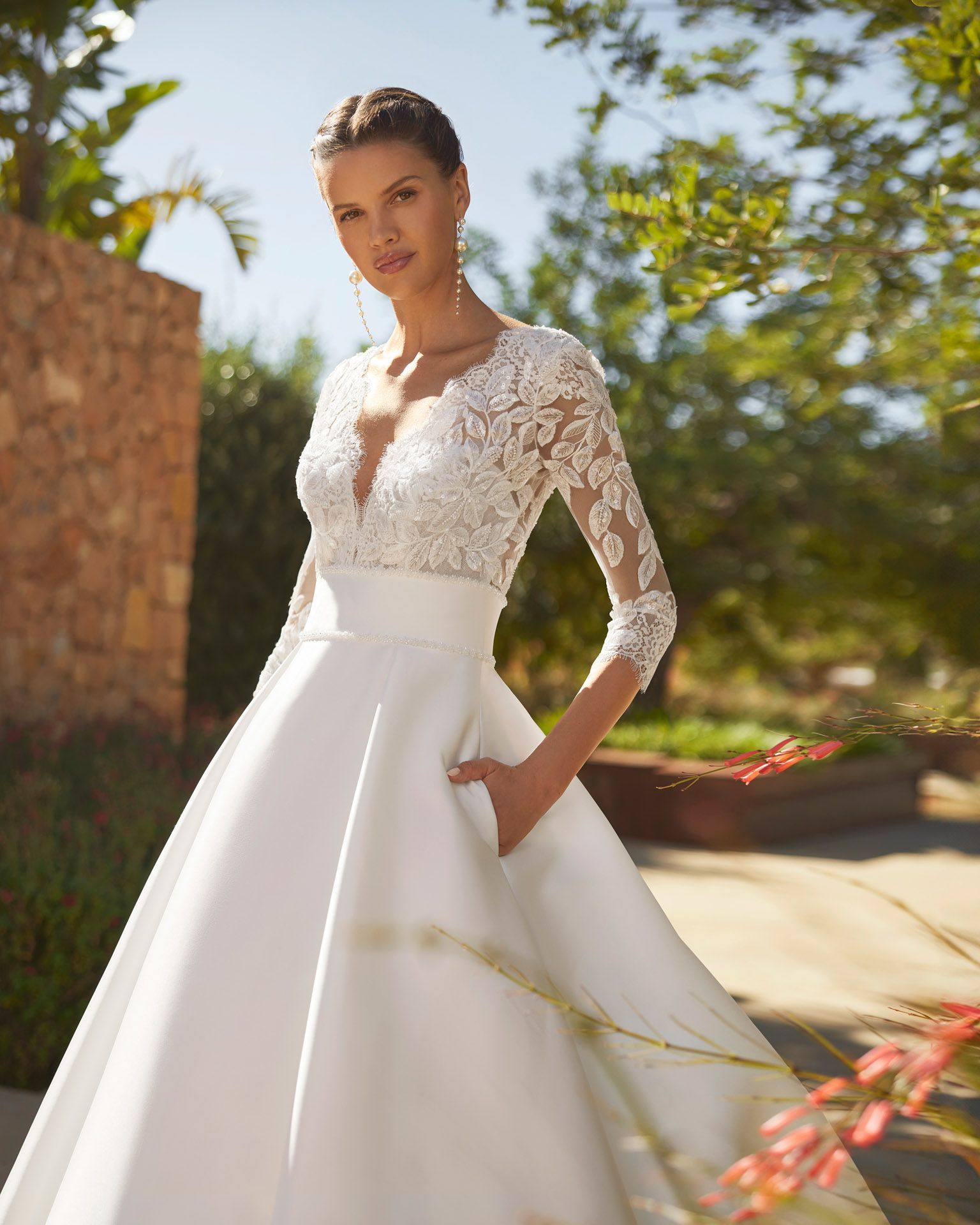 Donna in abito da sposa bianco con corpetto in pizzo, tasche, all'aperto, alla luce del sole.