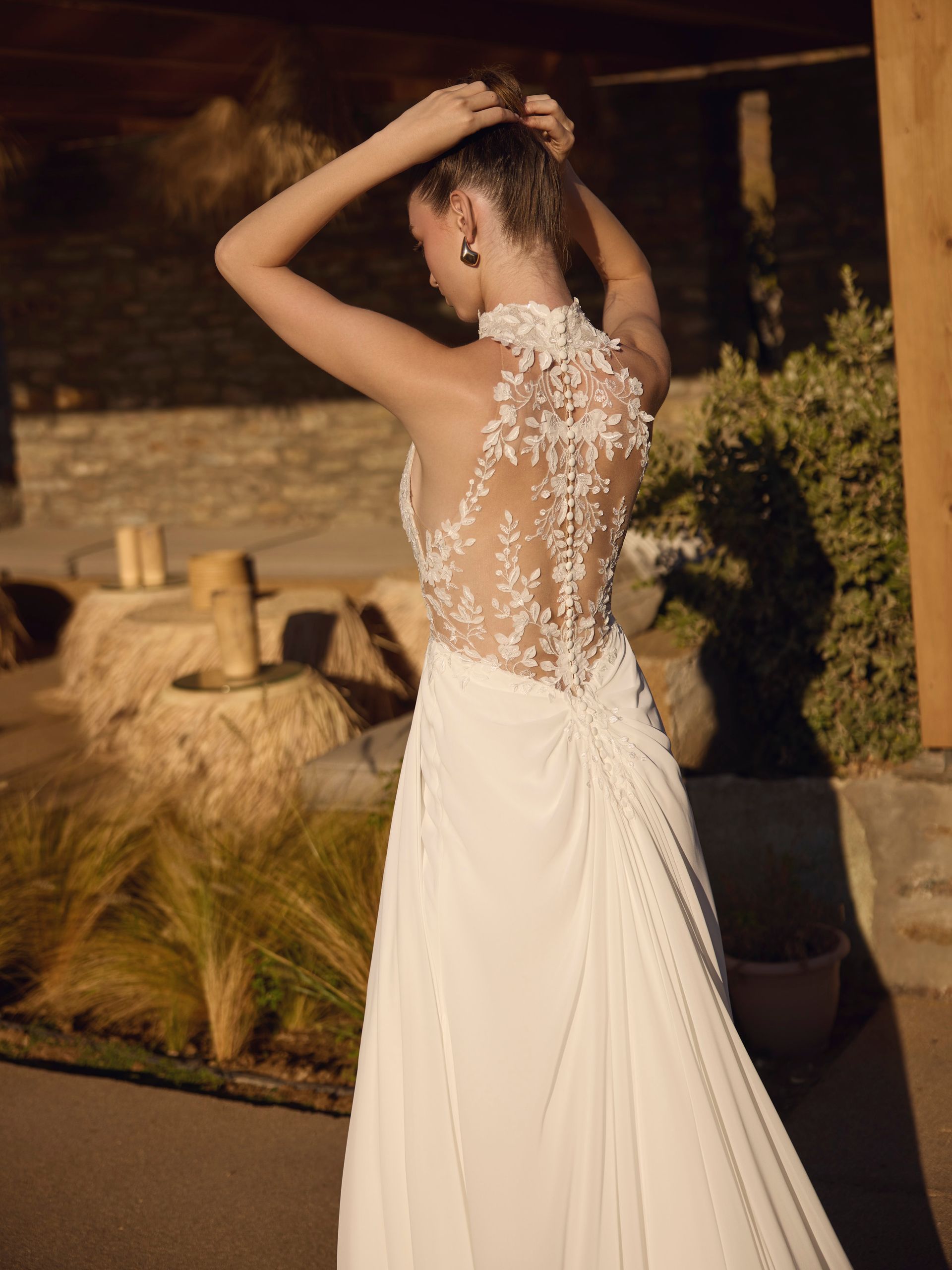 Donna in abito da sposa con schiena in pizzo, all'aperto.