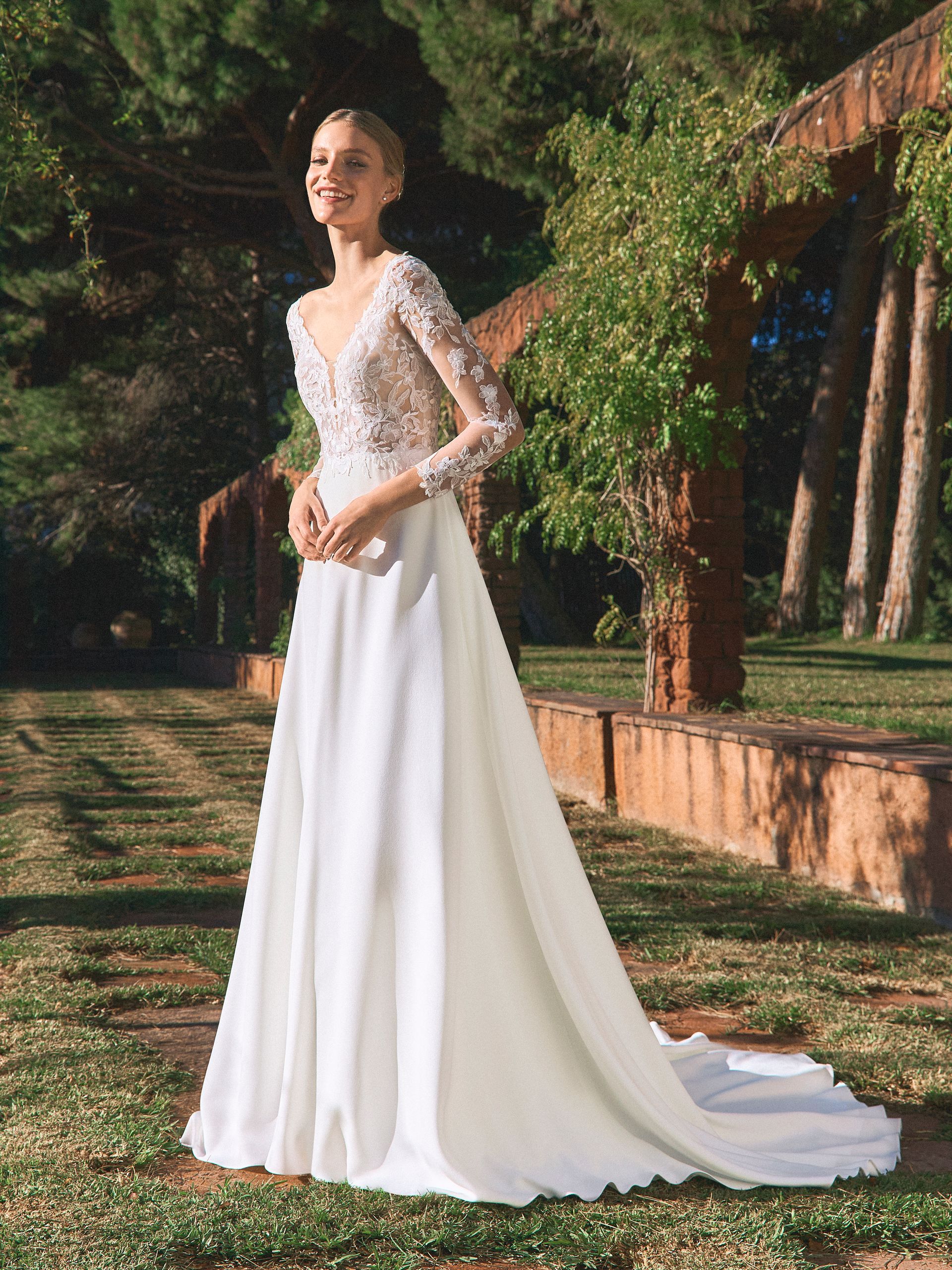La sposa in abito da sposa bianco sorride all'aperto.