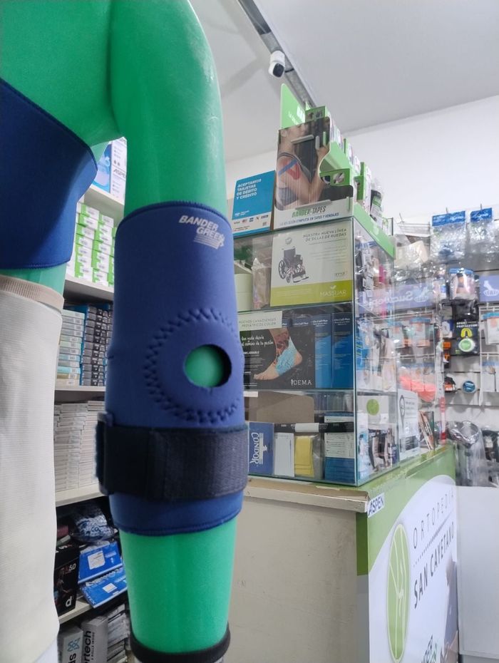 Primer plano de la pierna de un maniquí verde y azul con una rodillera en el pasillo de una tienda.