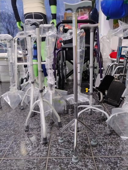 Andadores y bastones de metal plateado dispuestos sobre un suelo de baldosas en una tienda o clínica.