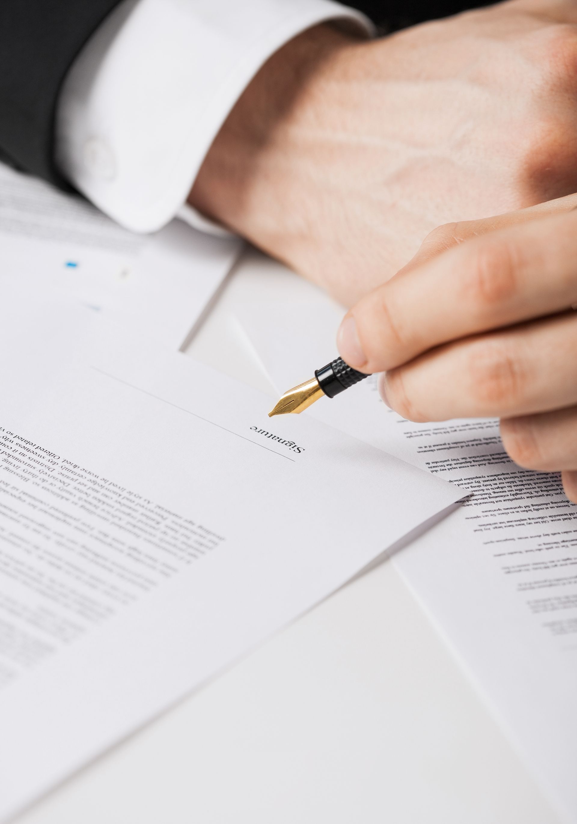 Hand with pen pointing to text on a white paper.