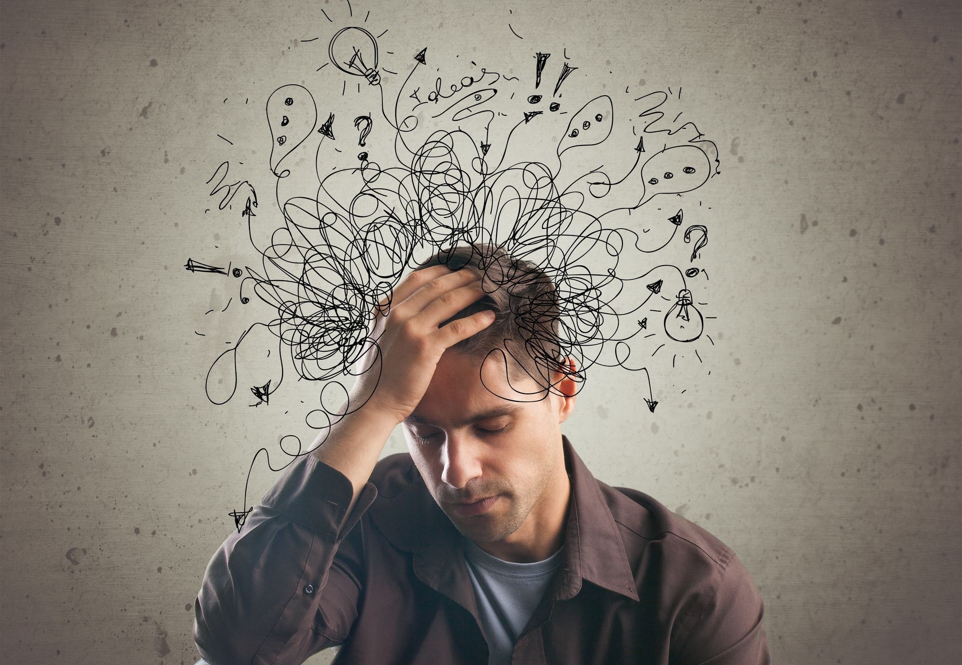 A man is holding his head with drawings coming out of it.
