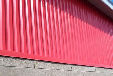A close up of a red metal fence on a brick wall.