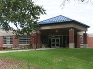 A brick building with a blue roof and a tree in front of it.