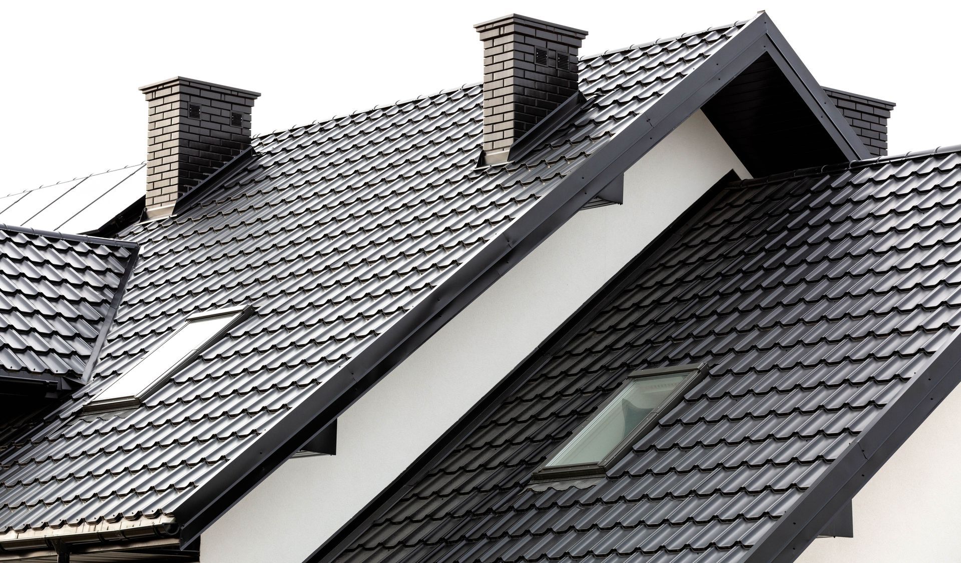 Residential house with metal roofing, skylights, and ceramic chimneys.