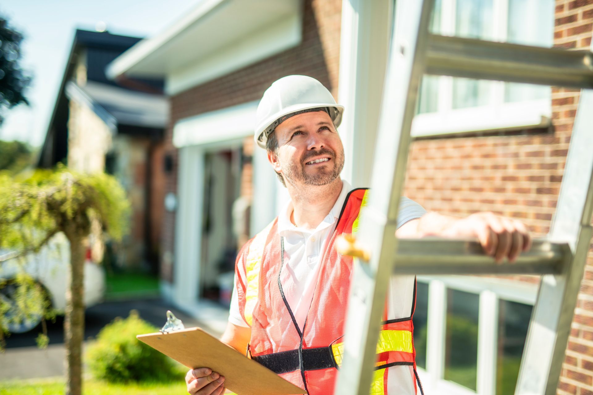 Roofing professional holding a clipboard beside a ladder.