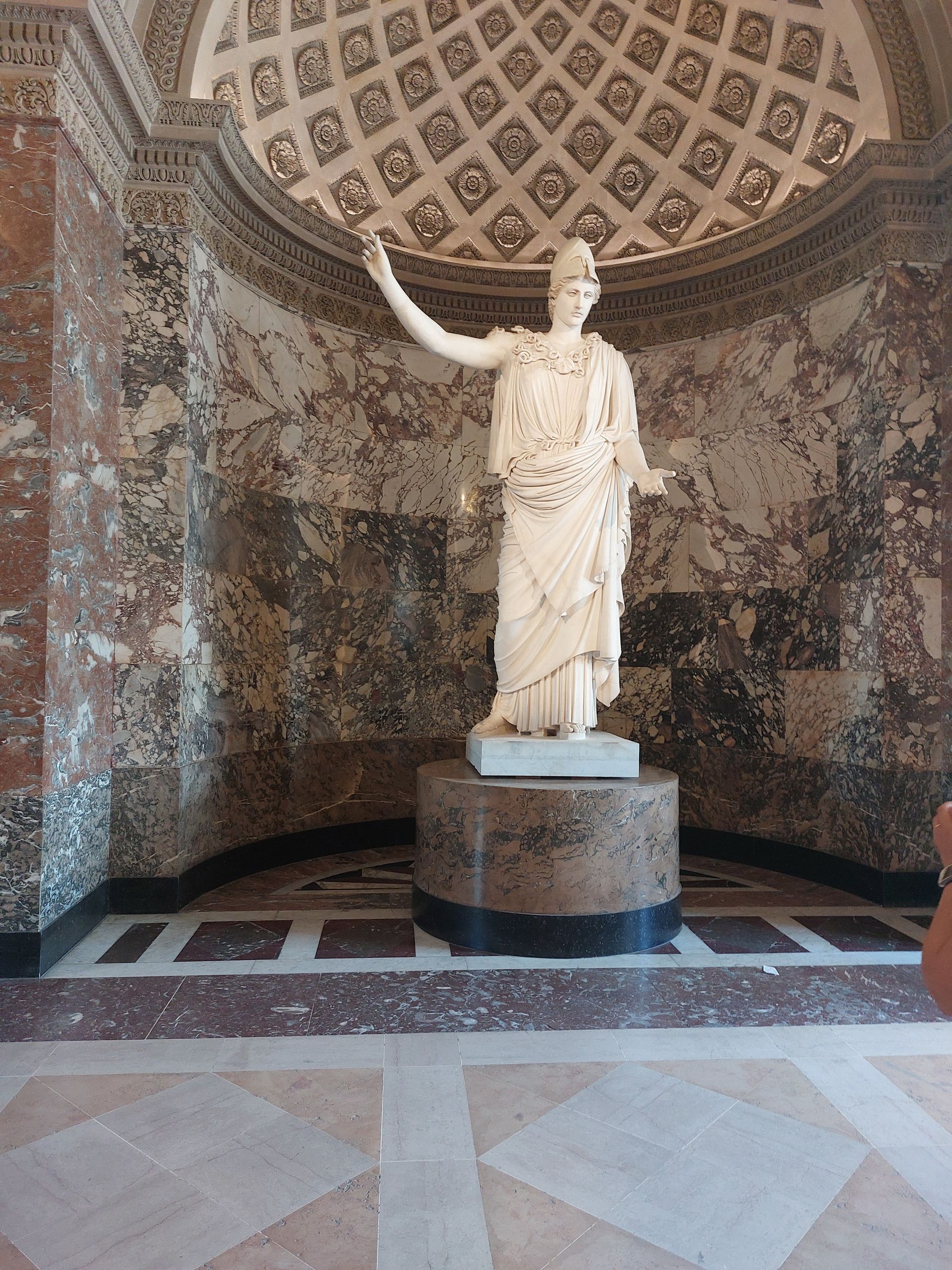 Statua in una nicchia a cupola con pareti decorate. La statua è in marmo bianco, su un piedistallo circolare.