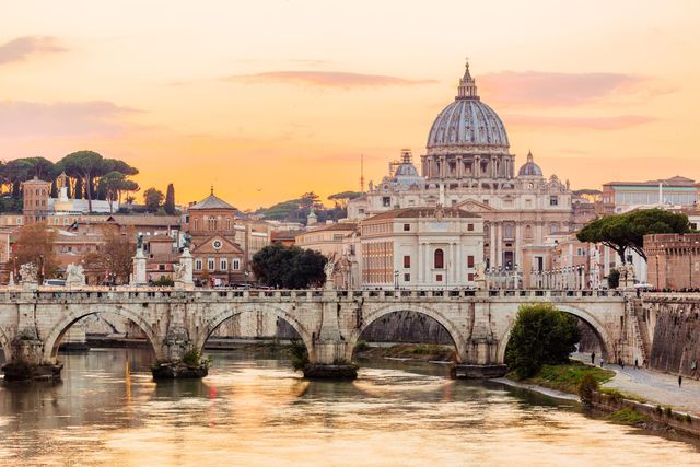 Ponte sull'acqua, sullo sfondo la cupola della Basilica di San Pietro, Roma, Italia, al tramonto.